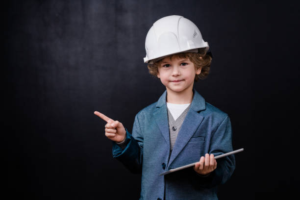 istock Cute little engineer with digital tablet looking at you and pointing aside 1195251046