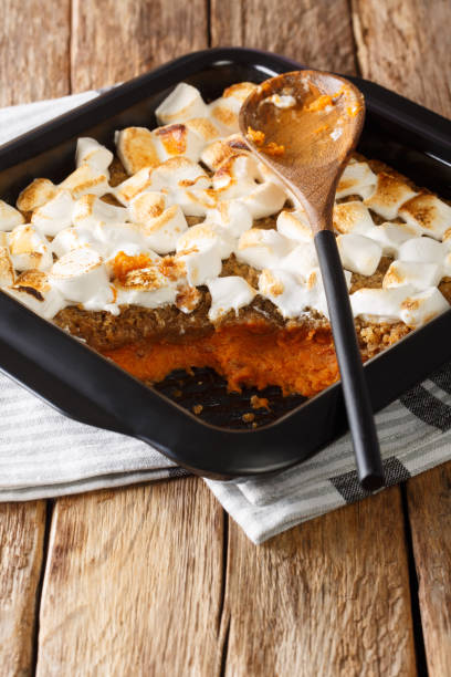 istock Festive sweet potato dessert with pecans and marshmallows close-up in a baking dish. vertical 1195251064
