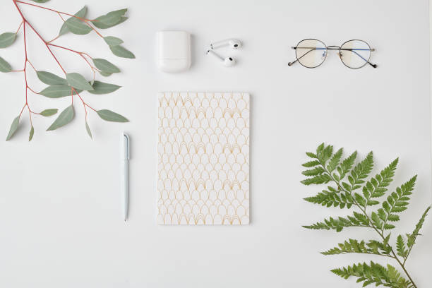 Flatlay of notebook with pen, eyeglasses and earphones on white background Flatlay of notebook with pen, eyeglasses and earphones on white background surrounded by green plants medical accessories stock pictures, royalty-free photos & images