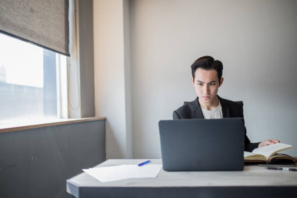 istock Young man sitting in office and working on notebook. Businessman checking his note and notebook while working in office. 1195252842