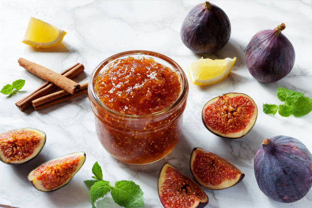 Fresh figs, with a dish of homemade fig jam or preserves marmalade kitchen marble table background. stock photo