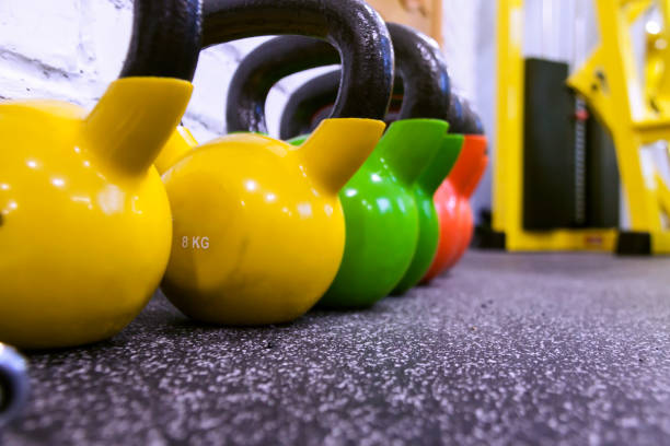 istock Colorful kettle bells in a row black gym floor background with copy space 1195254229