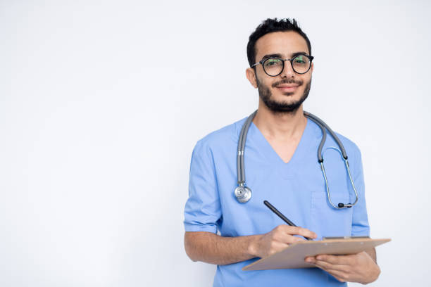 青い制服で幸せな若い成功した男性の臨床医は処方箋を作る - scrubs surgeon standing uniform ストックフォトと画像