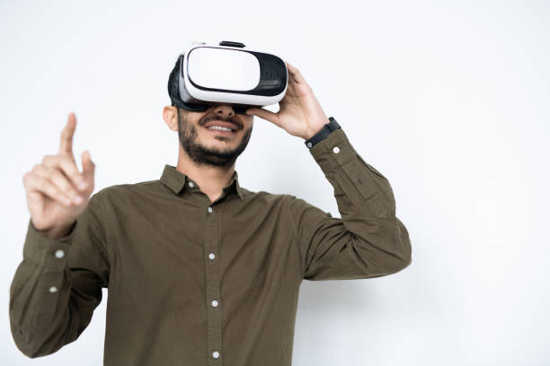 istock Contemporary guy with vr headset pointing at virtual display during presentation 1195258297