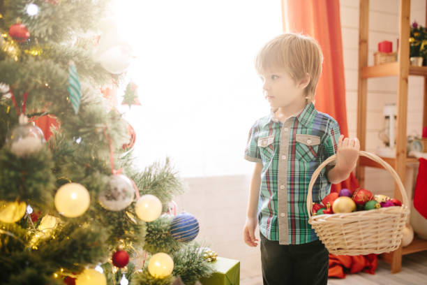 istock Cute little boy of about five year with blue eyes decorating a Christmas tree. 1195259444