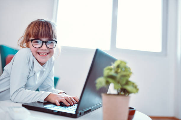 istock Cute Female Child Typing On Laptop 1195262696