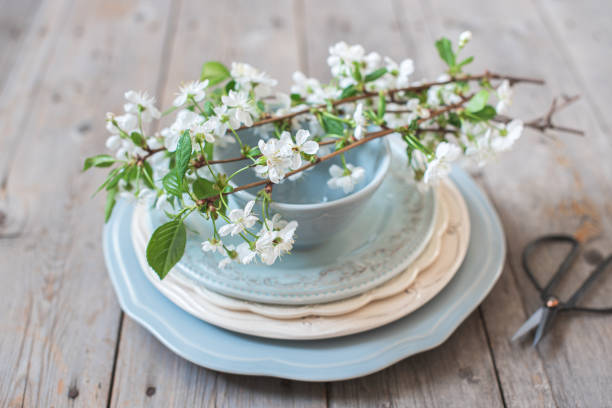 istock Branches of white cherry blossoms on a stack of blue plates and scissors 1195262699