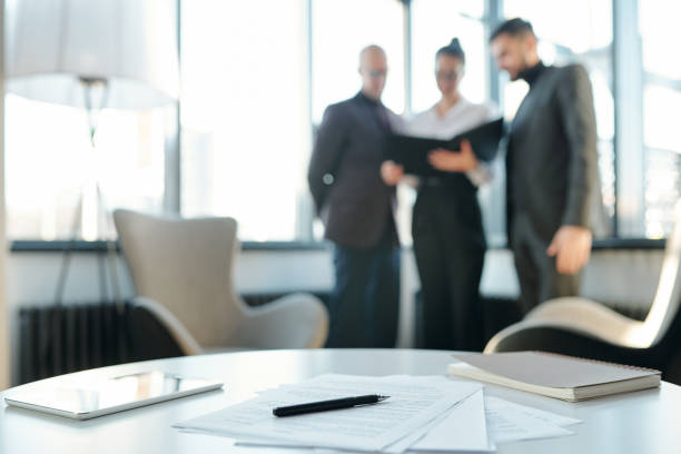 istock Touchpad, notebook, papers and pen on table on background of colleagues 1195264004