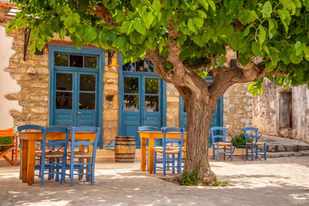 mesas y sillas en el patio de la taberna - greek islands table window sun fotografías e imágenes de stock