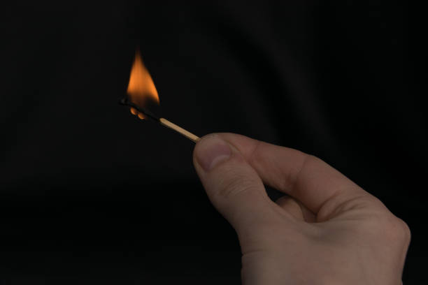 istock burning match in hand on black background 1195268083