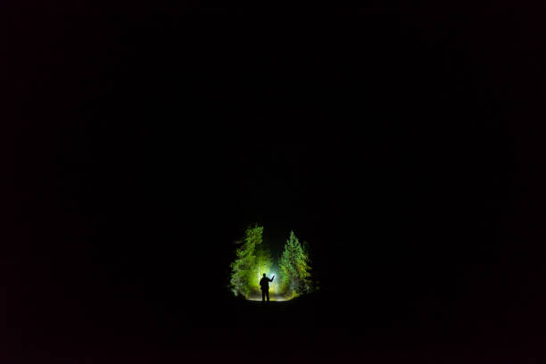 istock Man standing outdoor at dark night shining with flashlight 1195272099