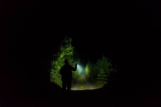 istock Man standing outdoor at dark night shining with flashlight 1195272121