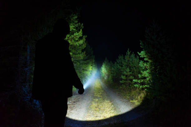 istock Man standing outdoor at dark night shining with flashlight 1195272199