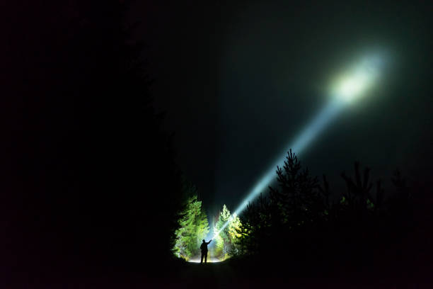 istock Man standing outdoor at dark night shining with flashlight 1195272228