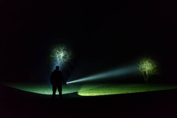 istock Man standing outdoor at dark night shining with flashlight 1195272266