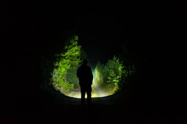 istock Man standing outdoor at dark night shining with flashlight 1195272273