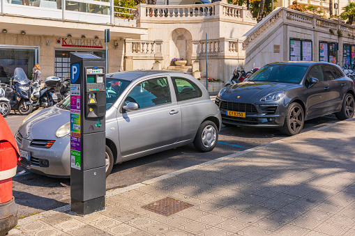 San Remo, Italy - Apr 18, 2019: Parking automat and parked cars on the street in San Remo at morning