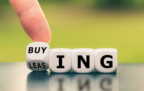 Hand turns a dice and changes the word "leasing" to "buying", or vice versa.