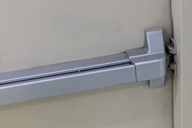 istock Emergency fire exit door. Closed up latch and rusty door handle of emergency exit. Push bar and rail for panic exit. Open one way door.  steel of handle for the white door fire exit 1195282293