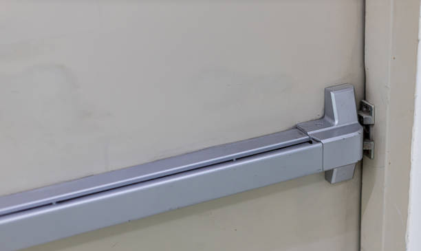 istock Emergency fire exit door. Closed up latch and rusty door handle of emergency exit. Push bar and rail for panic exit. Open one way door.  steel of handle for the white door fire exit 1195282294