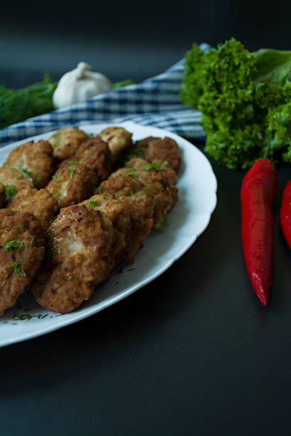 istock Pork cutlets on a plate with greens and vegetables on a black background. View from above. 1195283162