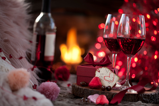 Valentine's Day Red Wine and a Gift with Chocolates in Front of the Fireplace