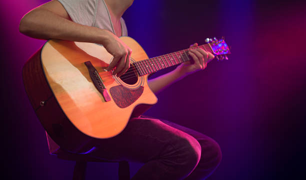 istock The musician plays an acoustic guitar. Beautiful background with colored light rays. 1195292321