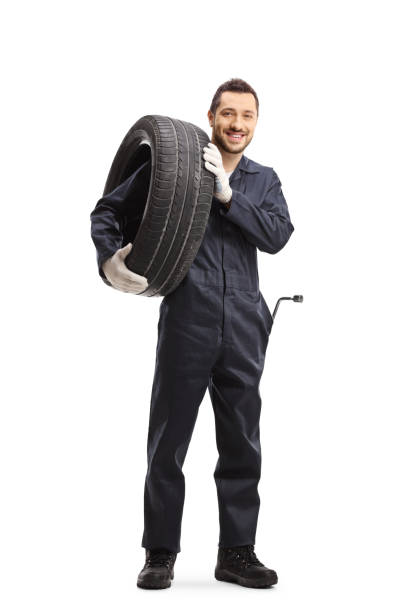 istock Auto mechanic carrying a tire and smiling at the camera 1195294001
