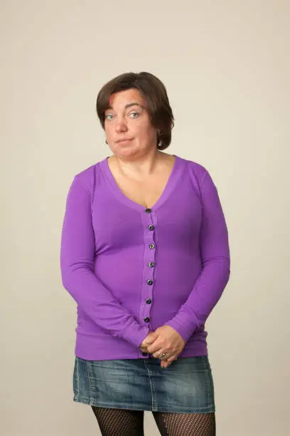 Close-up studio portrait of a 40 year old woman in purple cardigan on beige background