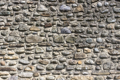 Stone wall. Masonry stones. Building construction. Medieval construction technology. The exterior of the building. The texture of the stones. An element of architecture. Brick background.