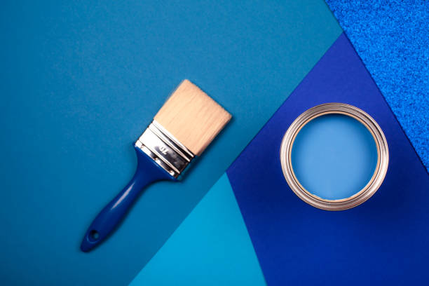 istock Brush on open can of blue paint on blue background. 1195307874
