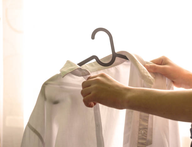 istock The young man's hands remove the white shirt from the hanger 1195352308
