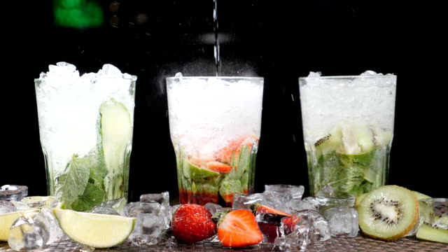 Bar and cocktail concept. Bartender prepare different Mojito Cocktails. Close up. Splashes. Slow motion.