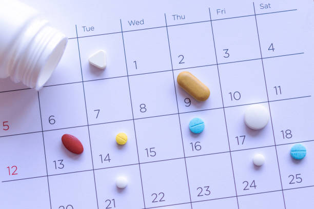 bunch of different pills on a calendar background. concept healthcare - vitamin pill capsule equipment data imagens e fotografias de stock