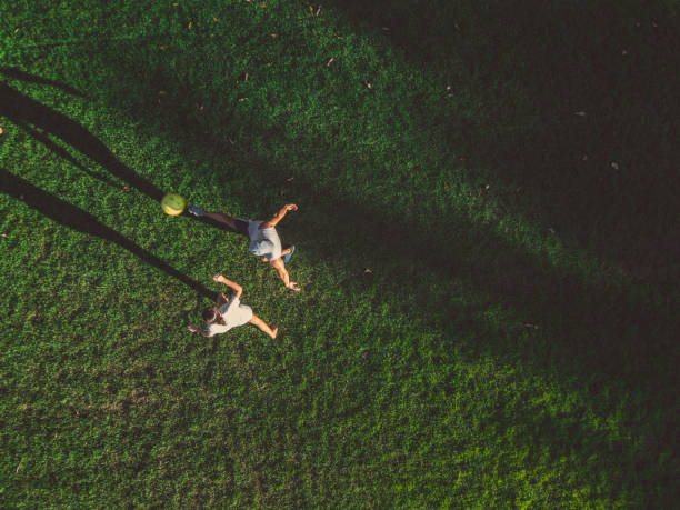 drone view on green meadowt with man and girl playing soccer