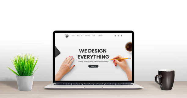 istock Web design studio concept. Latop with modern, flat design agency web page on desk. Plant and cup of coffee beside 1195366426