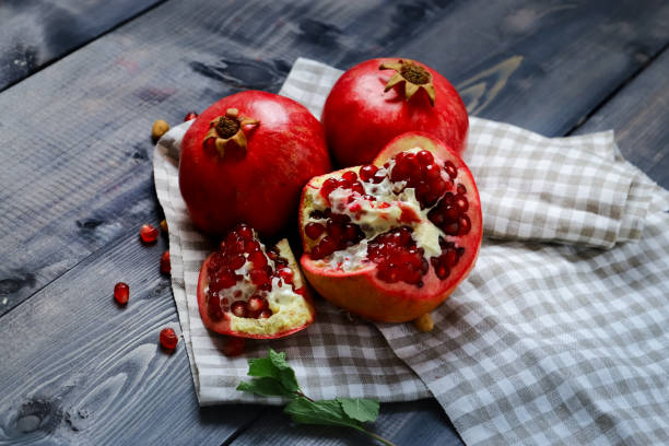 istock Red pomegranates, one broken and bright transparent grains visible 1195370228
