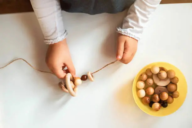 Photo of Childs hands threading beads and making bracelet.