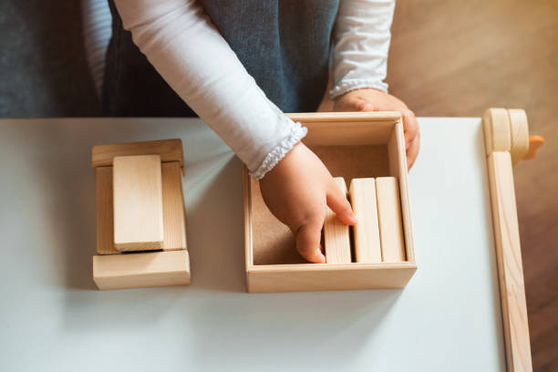 menina que joga com tijolos de madeira em casa. - building activity block human hand house - fotografias e filmes do acervo