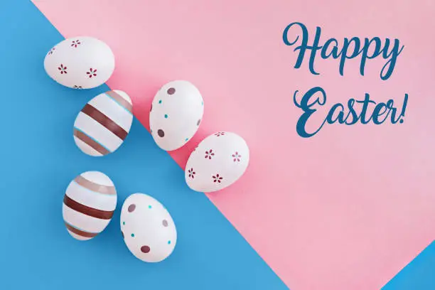 Eggs decorated with stripes and flowers on pink and blue background, Easter concept with text.