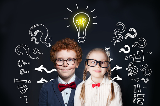 Brainstorming and idea concept. Smart successful children girl and boy student with lightbulb on blackboard background