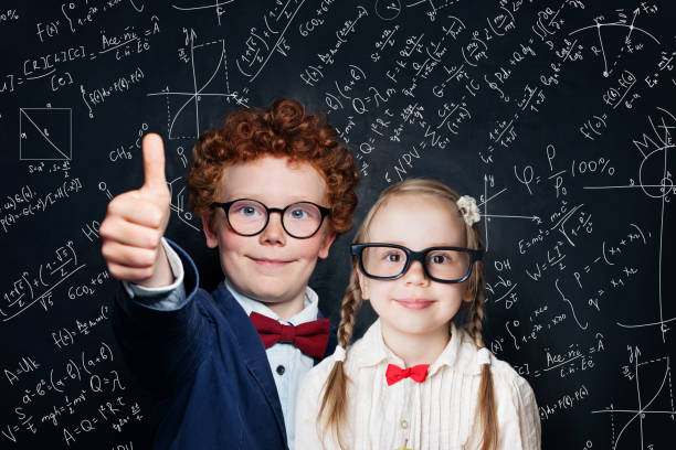 istock Happy little kids in school uniform having fun on blackboard background with science formulas, back to school concept 1195373552