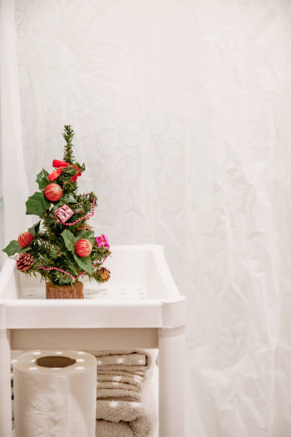 Christmas decor, decorated Christmas little tree stands on a shelf in the bathroom on a white background stock photo