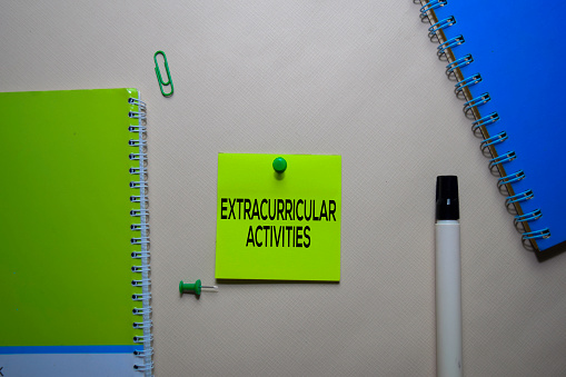 Extracurricular Activities text on sticky notes at office desk.