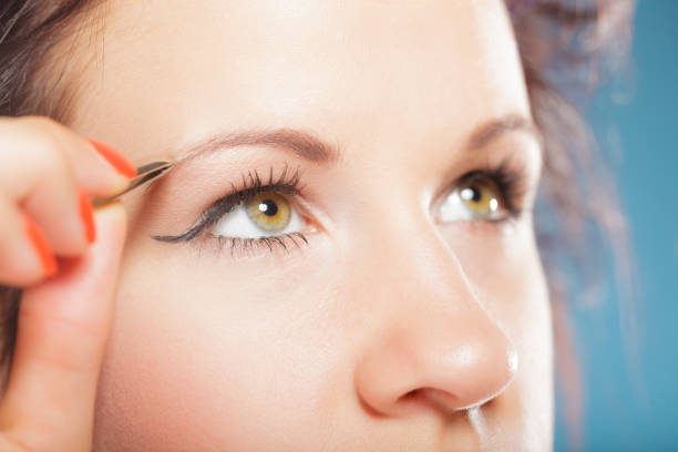 istock Girl tweezing eyebrows closeup 1195382904