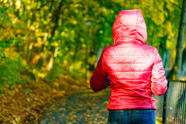 istock Woman in red jacket walking in autumn park 1195385018