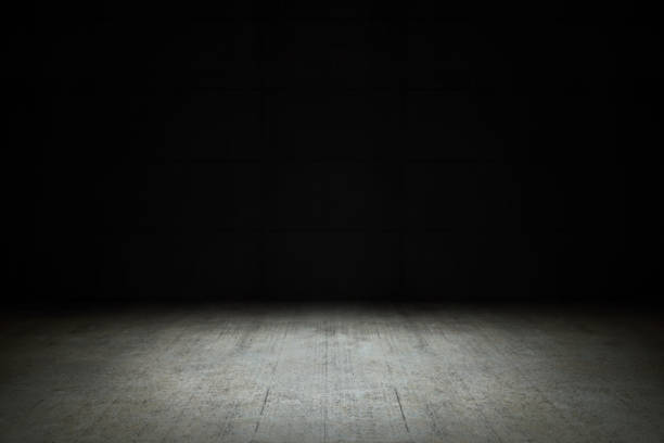 istock Dark empty room with black background and dim light on concrete floor 1195388222