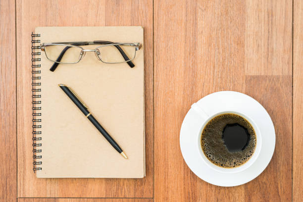 istock Top view eyeglasses and pen on notepad and coffee cup on wood deck with copy space 1195390386