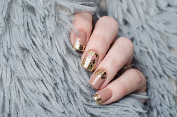 istock beige Nude manicure with gold lace pattern on a gray background 1195392475