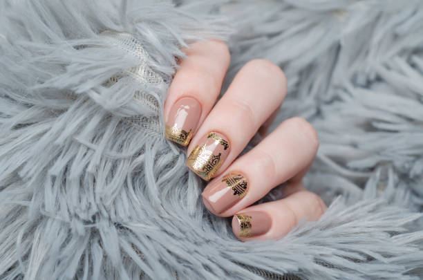 istock beige Nude manicure with gold lace pattern on a gray background 1195392505